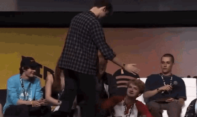 a man in a plaid shirt is standing in front of a crowd of people .