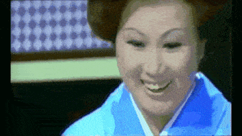 a woman in a blue kimono is smiling in a pixelated video .