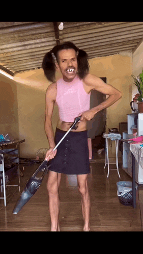 a man with pigtails is holding a vacuum cleaner in his hand