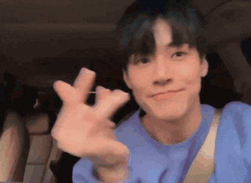 a young man in a blue sweater is waving his hand .
