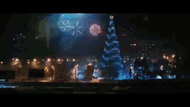 a christmas tree is surrounded by fireworks in the night sky
