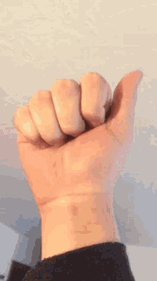a close up of a person 's fist with their thumb pointing up