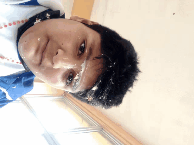 a boy with cake on his face is looking down at the camera