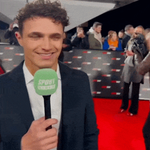 a man in a suit is holding a green microphone that says sport on it