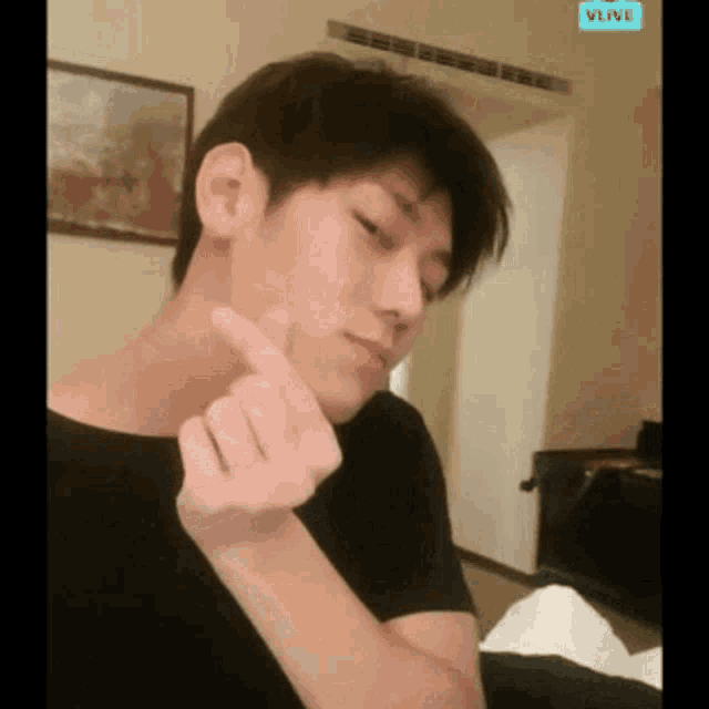 a man in a black shirt is making a heart shape with his finger .