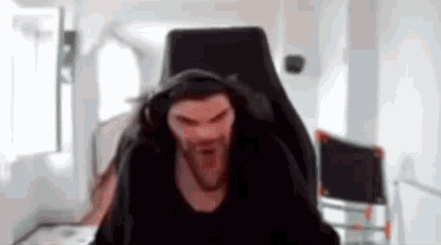 a man with a beard is sitting in a gaming chair with headphones on .
