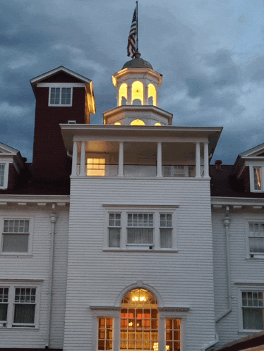 a large white house with a red roof and a clock tower