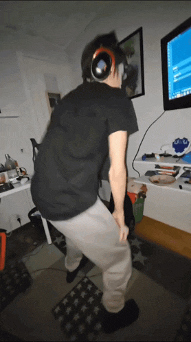 a man wearing headphones is dancing in front of a television