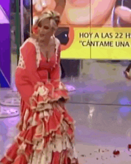 a woman in a red dress is standing in front of a yellow sign that says hoy a las 22 h