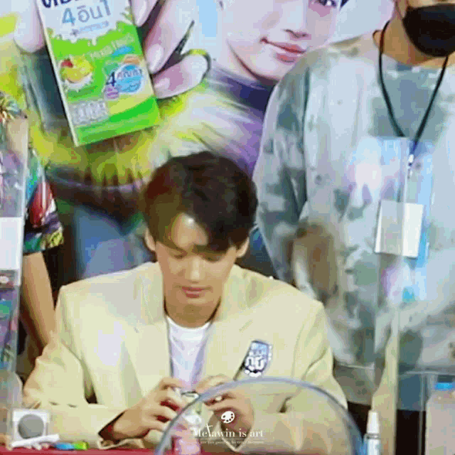 a man in a suit is sitting at a table holding a box of juice