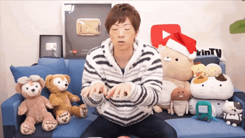 a man is sitting on a couch with stuffed animals and a sign that says trinty