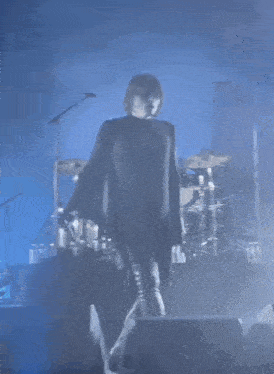 a man in a black cape is standing on a stage