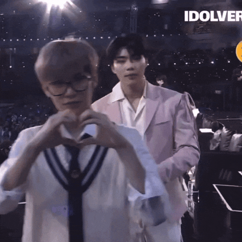 two men are making a heart shape with their hands in front of a crowd with the word idolver on the bottom