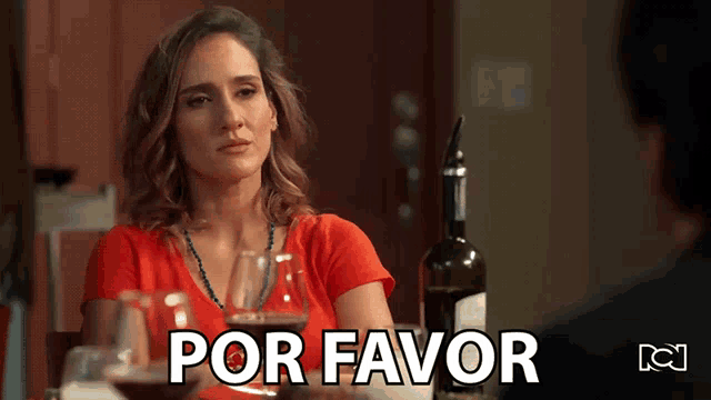 a woman sits at a table with a bottle of wine and a sign that says por favor on it