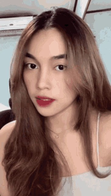 a close up of a woman 's face with a white air conditioner in the background