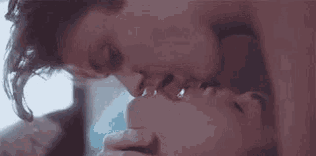 a man and a woman are kissing each other in a room .