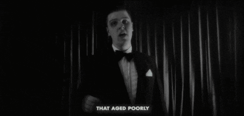 a man in a tuxedo is standing in front of a curtain with the words that aged poorly below him