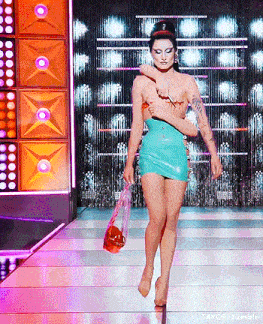 a woman in a blue dress is walking down a runway holding a bloody bag
