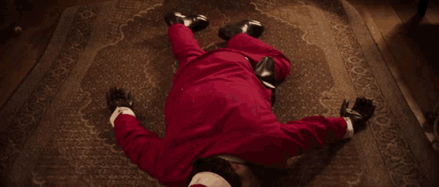 a man dressed as santa claus is laying on his back on a rug