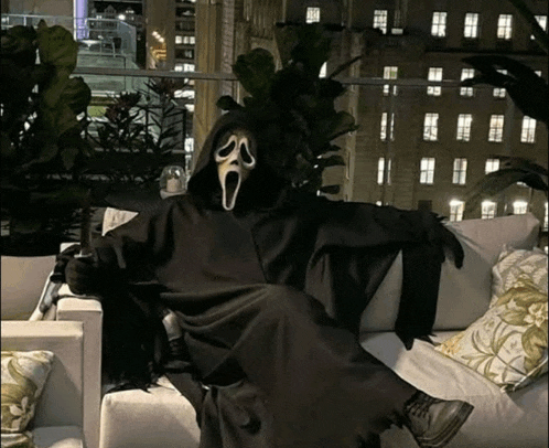 a person in a scream costume sits on a couch