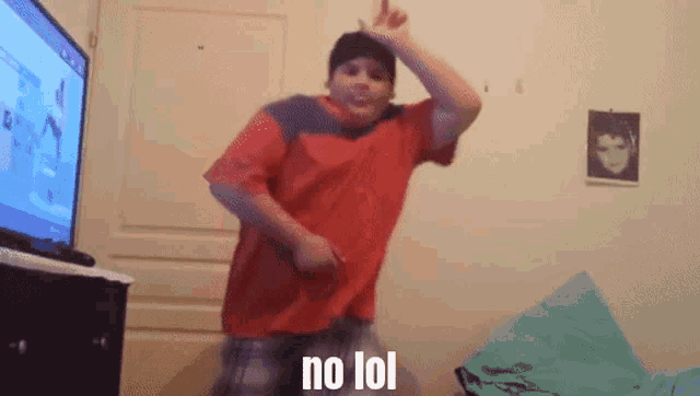 a boy in a red shirt is dancing in front of a tv and the words no lol are visible