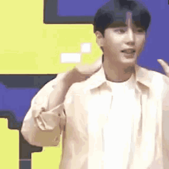 a young man in a white shirt is standing in front of a yellow and purple wall .
