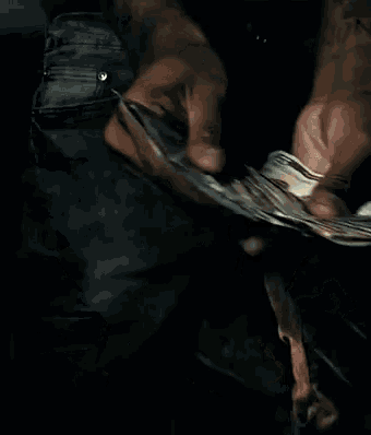a man is holding a fan of 20 dollar bills in his hands