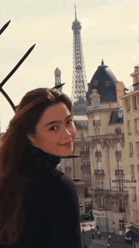 a woman stands in front of the eiffel tower