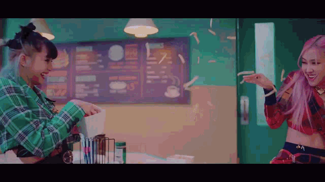 two women are standing next to each other in a restaurant with french fries falling around them .