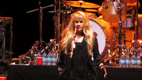 a woman singing into a microphone on a stage with water bottles