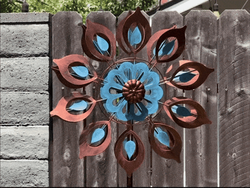 a peacock feather wind spinner is hanging on a fence