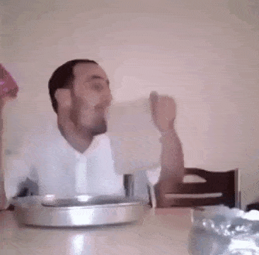 a man is sitting at a table with a bowl of food and a pitcher of water .
