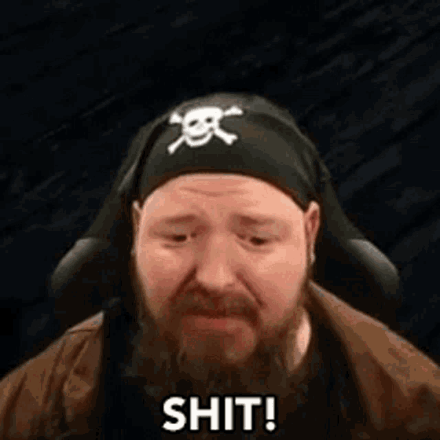 a man with a beard is wearing a pirate hat and headphones and says `` shit ! ''