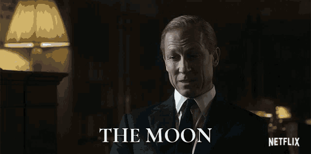 a man in a suit and tie is talking to someone with the moon written above him