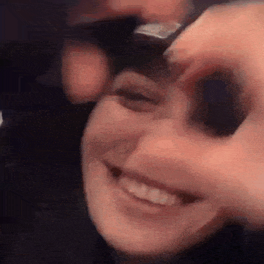 a close up of a woman 's face with a man 's hand holding her eye .