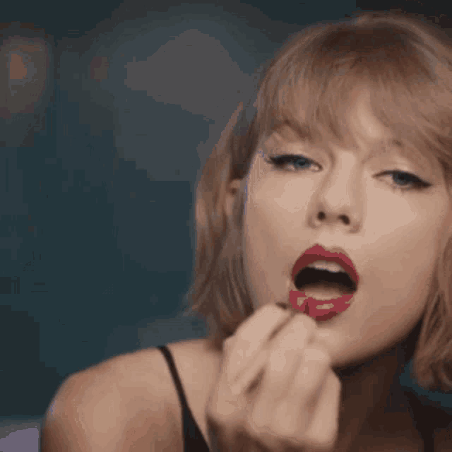 a woman is applying red lipstick on her lips