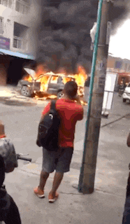 a man is taking a picture of a car on fire