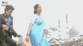a woman in a blue dress is standing in a park .