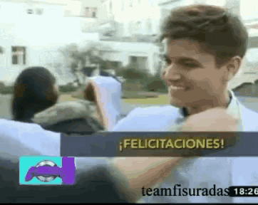 a man is smiling in front of a sign that says felicitaciones on it