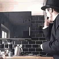 a man in a top hat stands in a kitchen