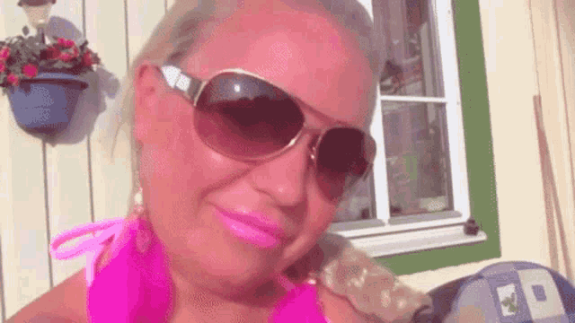 a woman wearing sunglasses and a pink shirt with a letter p on it