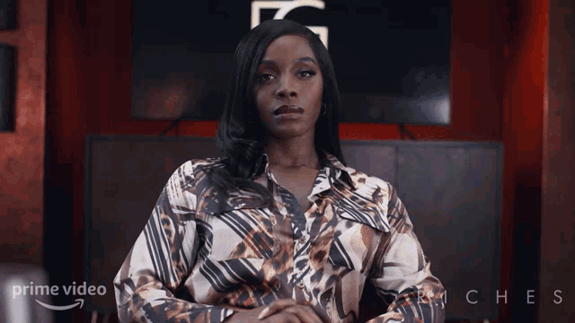 a woman sitting in front of a screen that says prime video on it