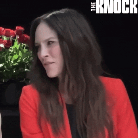 a woman in a red jacket is sitting in front of a sign that says ' the knock ' on it
