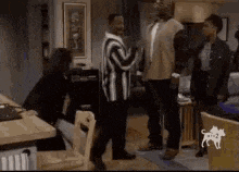 a group of people are standing in a living room and talking to each other .