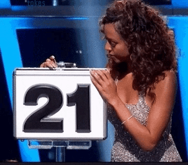 a woman in a silver dress holds a sign that says 21