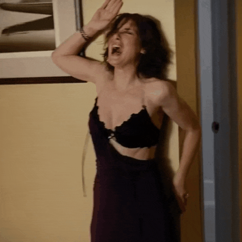 a woman in a black bra is standing in a doorway and screaming .