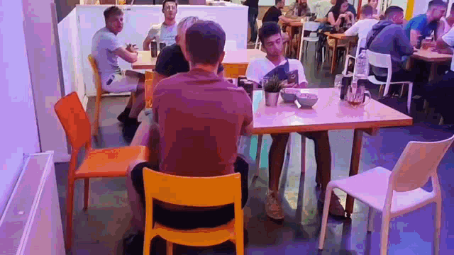 a man is sitting at a table in a restaurant looking at a menu .