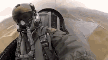 a fighter jet pilot wearing a helmet , goggles , and an oxygen mask is flying through the air .