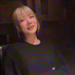 a woman with blonde hair is sitting in a dark room with her mouth open .