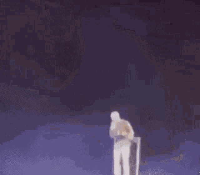 a man in a yellow jacket and white shorts is standing on a stage .